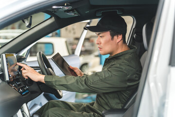 Male auto mechanic using a tablet device inside a car
