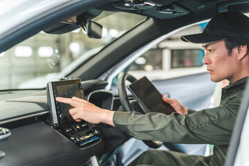Male auto mechanic using a tablet device inside a car

