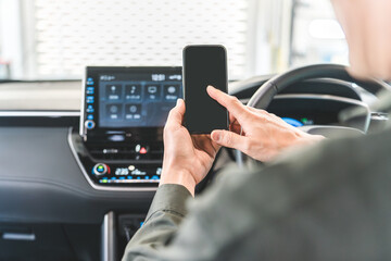 Male auto mechanic using smartphone inside a car

