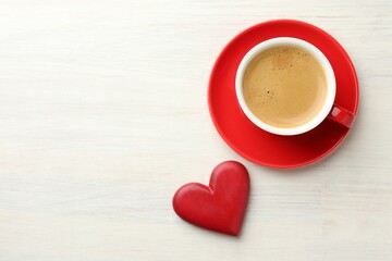 Heart figure and cup of coffee on white wooden table, top view. Space for text