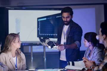 A robotics engineering team in an RD lab reviews a prototype. They are designing an AI powered robotic arm, analyzing data on a screen and a smart table.