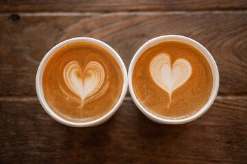 Couple cups of cappuccino coffee on wooden table. A cappuccino is the perfect balance of espresso, steamed milk and foam.