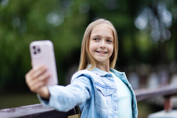 Young girl taking a selfie with smartphone in a park
