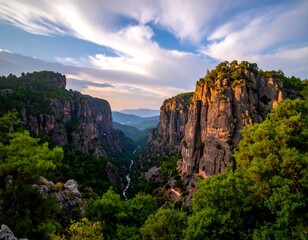 Naklejka premium Deep canyon landscape framed by cliffs, trees, and cloudy sky
