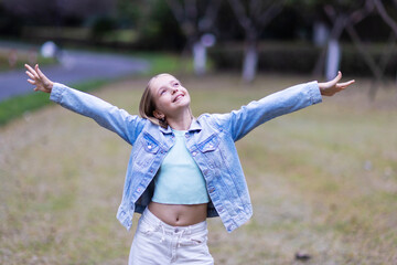 Young girl smiling with arms outstretched in a park