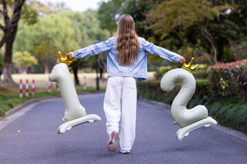 Young girl walking outdoors holding number balloons in park