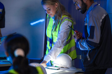 A diverse engineering team, a smiling Caucasian woman in a safety vest and an Indian man,...