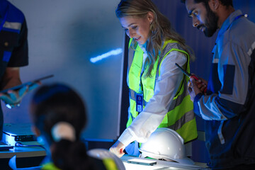 A diverse engineering team, a smiling Caucasian woman in a safety vest and an Indian man,...