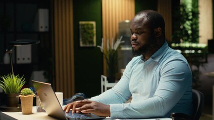 African american staff member distraught thinking about new ideas to impress the board, creating a presentation to help with development. Reflect about decisions and pushing limits. Camera B.