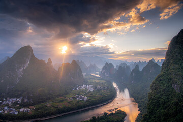 First rays of light through the clouds in Xianggong hill landscape of Guilin, Li River and Karst mountains. Xingping, Yangshuo County, Guangxi Province, China.