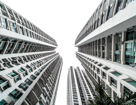 View looking up at tall, white apartment buildings against a black sky creating stark contrasting lines