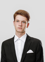 Portrait a Young man in a black suit adjusting his jacket in a studio