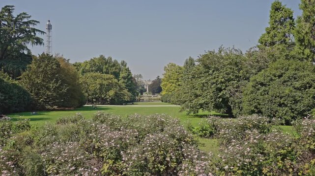 Tall trees and soft sunlight create a peaceful atmosphere, perfect for portraying relaxation, leisure, or daily life in an urban green space in Parco Sempione, Milan, filmed on September 15, 2025.