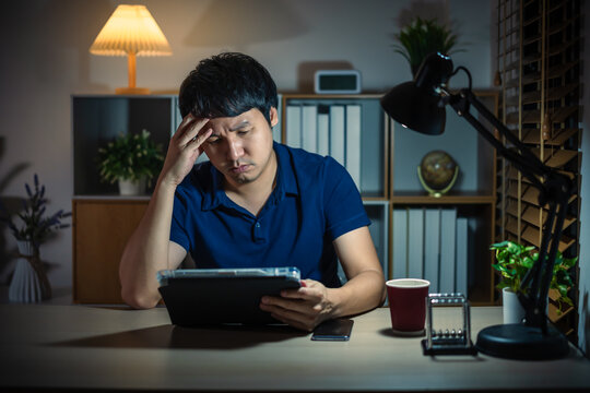 stressed man using tablet at night