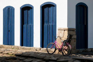 Pink bicycle with child seat by building with blue doors