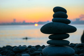 Balancing stones on the beach at sunrise