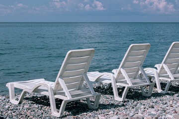 White sun loungers on a pebble beach by the sea
