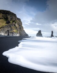 Dramatic coastal landscape with black sand and imposing rock formations