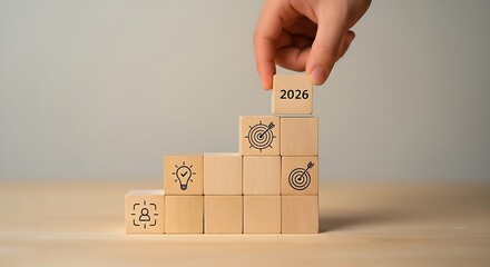 Hand placing the final wooden block with the word success to complete a rising staircase of blocks symbolizing growth and achievement