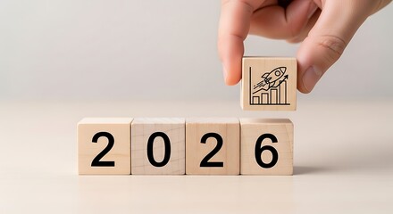 Hand placing a wooden block with a growth chart icon on top of the year 2026 symbolizing future success