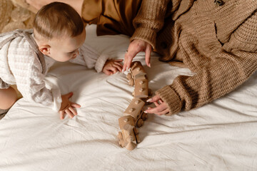 Mother and child on bed playing a game with a wooden train