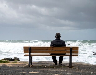 Elderly man sits on bench, gazing at stormy ocean waves