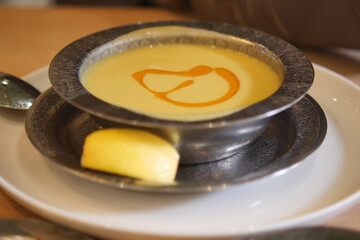Creamy soup served in a silver bowl with a lemon slice