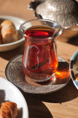 Warm cup of turkish tea served with sweets on a wooden table