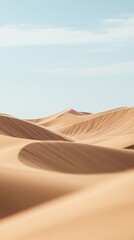 Sandy dunes under a light blue sky on a sunny day