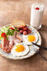 Fried eggs, sausages and bacon on a plate.