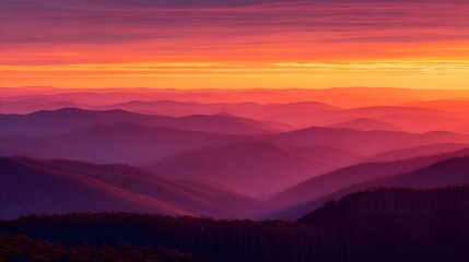 Fototapeta premium Layered mountain ranges fade into the distance beneath a dramatically colored twilight sky