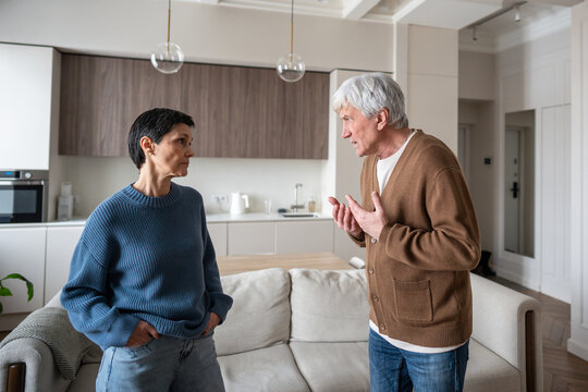 Furious elderly husband shouts at wife during bitter kitchen confrontation, senior spouses in crisis. Senior marital dispute, angry man in verbal confrontation, aging couple crisis, domestic unrest - Powered by Adobe