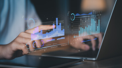 Business professional analyzing holographic financial charts on laptop and tablet, representing fintech analytics, investment dashboard, data-driven business strategy smart corporate decision making.