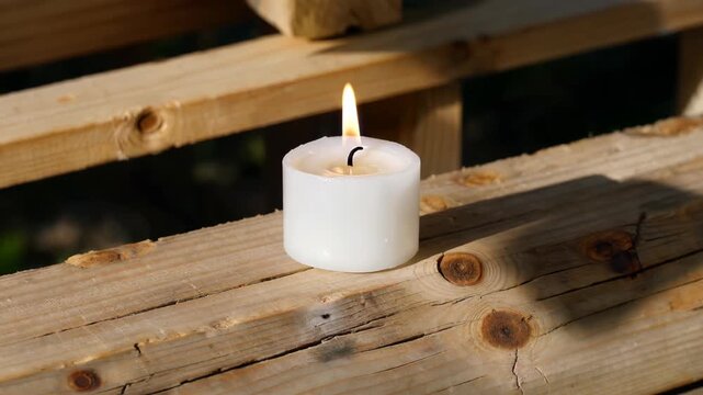 a close up of a candle on a wooden bench with a blurry background