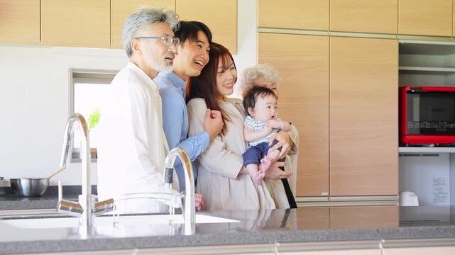 A smiling three-generation family surrounding a baby