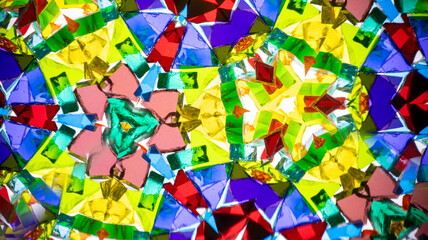 Vibrant kaleidoscope abstract pattern with symmetrical geometric shapes in purple, yellow, green,...