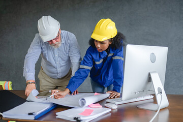 engineer wearing uniform sitting in front of computer, reviewing blueprints and documents...