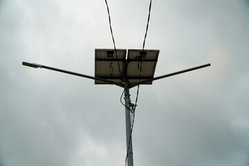 Solar powered street light with two panels against a cloudy sky.