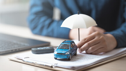 insurance, car, policy, coverage, claim, A miniature car with an umbrella on insurance documents symbolizes car insurance policy, financial protection, and risk coverage for vehicles and drivers. © Garun Studios