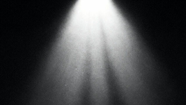Bright white spotlight beam illuminating downwards through darkness creating dramatic atmospheric light rays and shadows