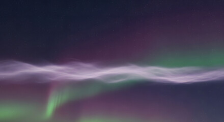 Vibrant green and purple aurora borealis illuminating the night sky with wavy light formations and vertical streaks of light.