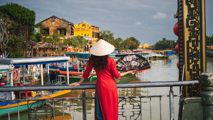 A woman in traditional Vietnamese cultural clothing in the ancient city of Hoi An on a bridge