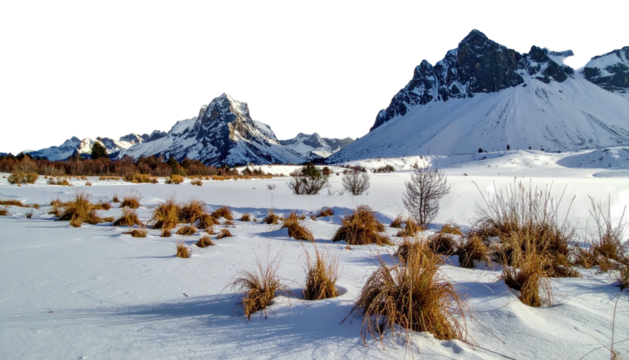 Snow-covered field before distant, jagged, mountains