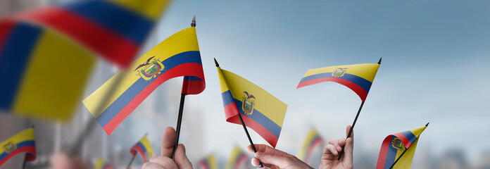 Ecuador flags in their hands on a blurred urban background