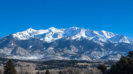 Panoramic alpine peaks coated in fresh snow, long ridges and rolling fields stretch across a cold clear winter day.