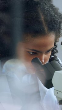 Scientist, woman and microscope in lab with inspection for sample analysis, biotech or stem cell research. Bokeh, person and equipment for science, medical innovation and cure development for cancer.