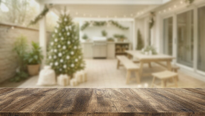 Empty wooden table with blurred background of patio decorated with Christmas tree, warm lights, and festive outdoor atmosphere.