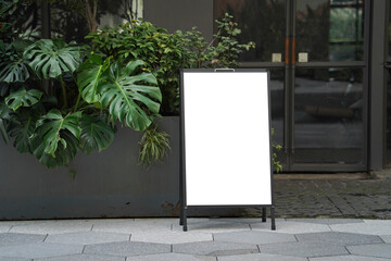 Blank white outdoor advertising stand or sandwich board mock up template. Clear street signage board placed by an outdoor dinning area of a restaurant. Background texture of standee on street.