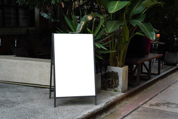 Blank white outdoor advertising stand or sandwich board mock up template. Clear street signage board placed by an outdoor dinning area of a restaurant. Background texture of standee on street.