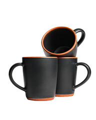 Stacked black mugs with orange trim on a dark background
